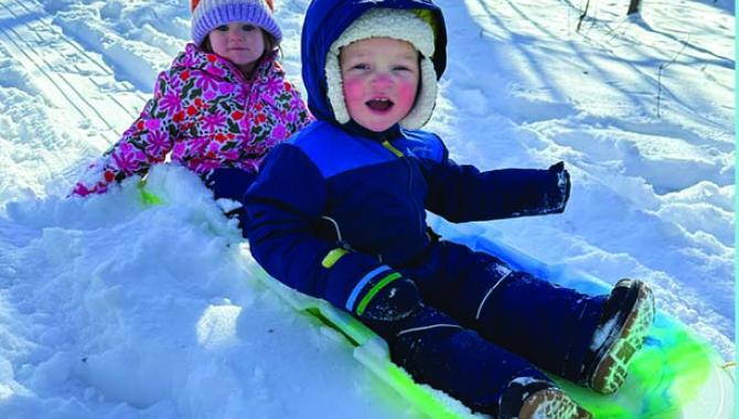 Two young children winter sleding