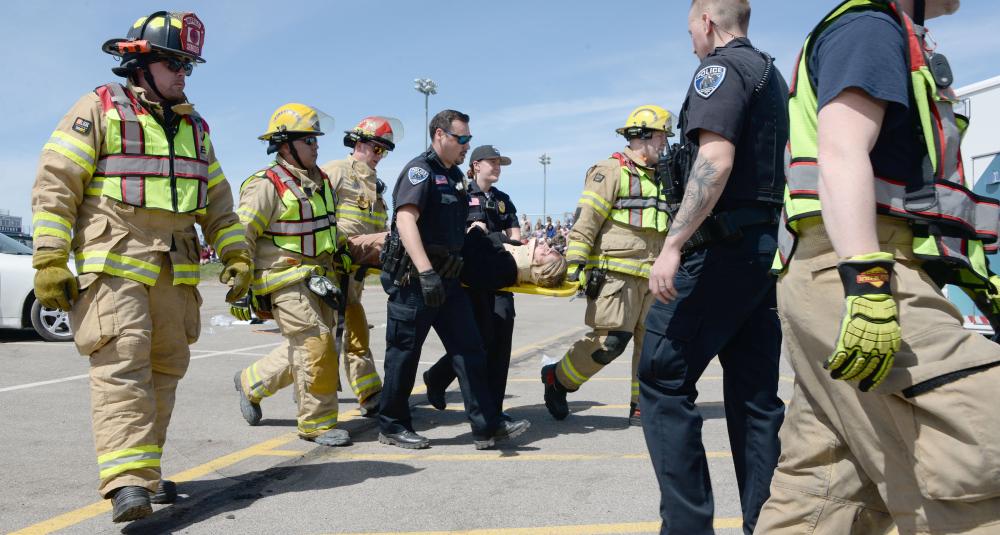 Emergency personnel take a mock crash victim to an ambulance.